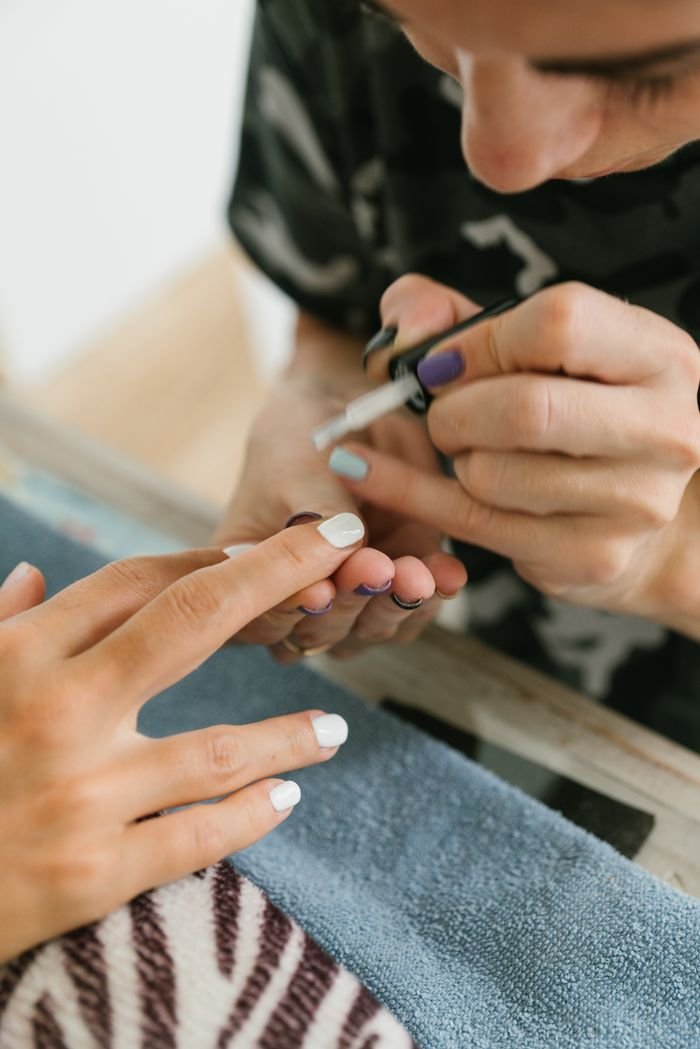 hero-img-01 Detailed view of a manicurist painting nails indoors, showcasing precision and care.
